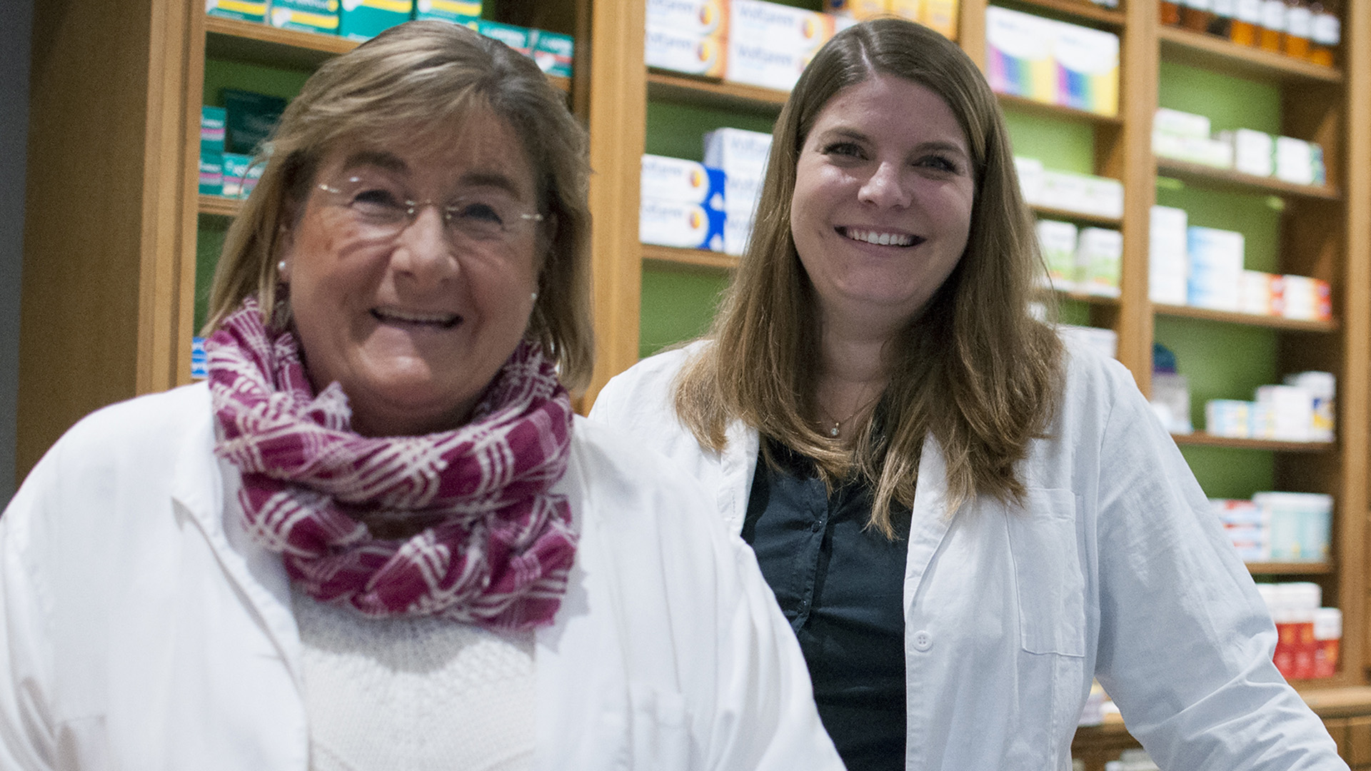 Ulrike Seyd und Theresa Bantele stehen vor der Auslage der Mohren-Apotheke. Die Inhaberinnen der Apotheke lächeln freundlich.